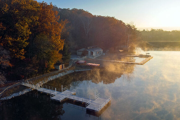 Aerial view of cabins and docks on a lake with morning fog.